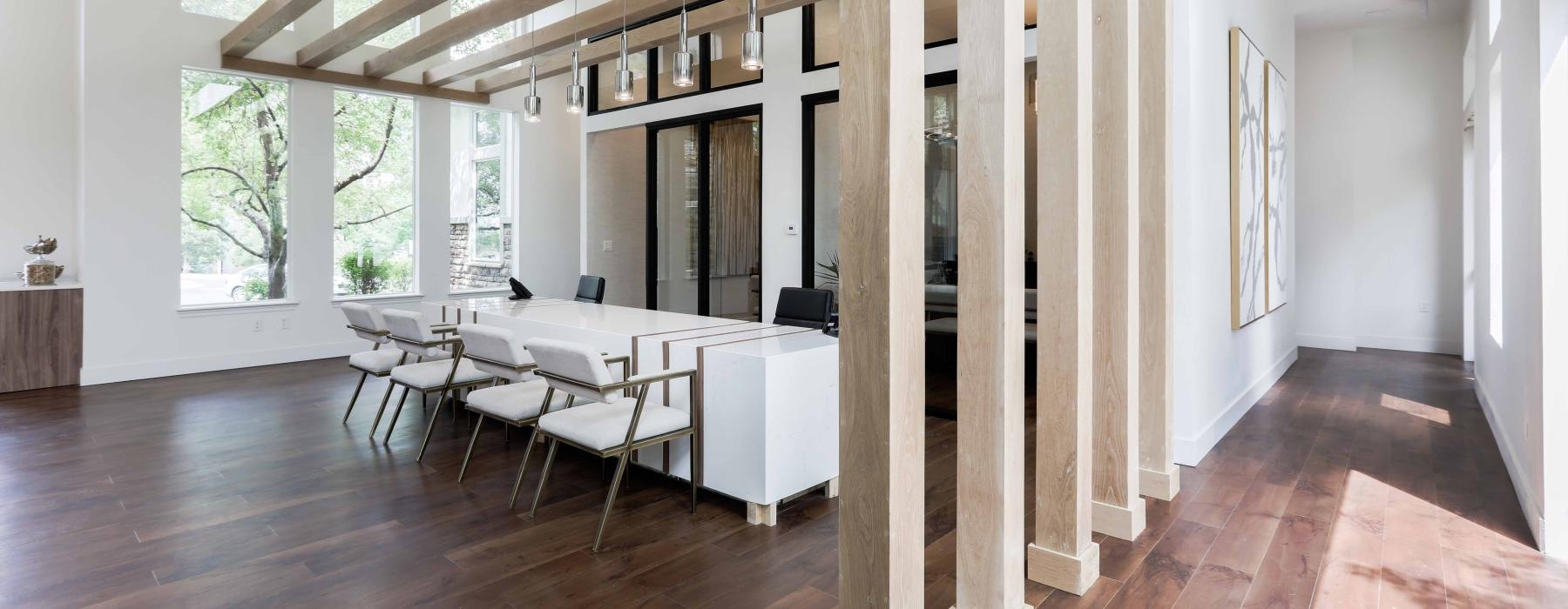 a room with a wood floor and white tables and chairs