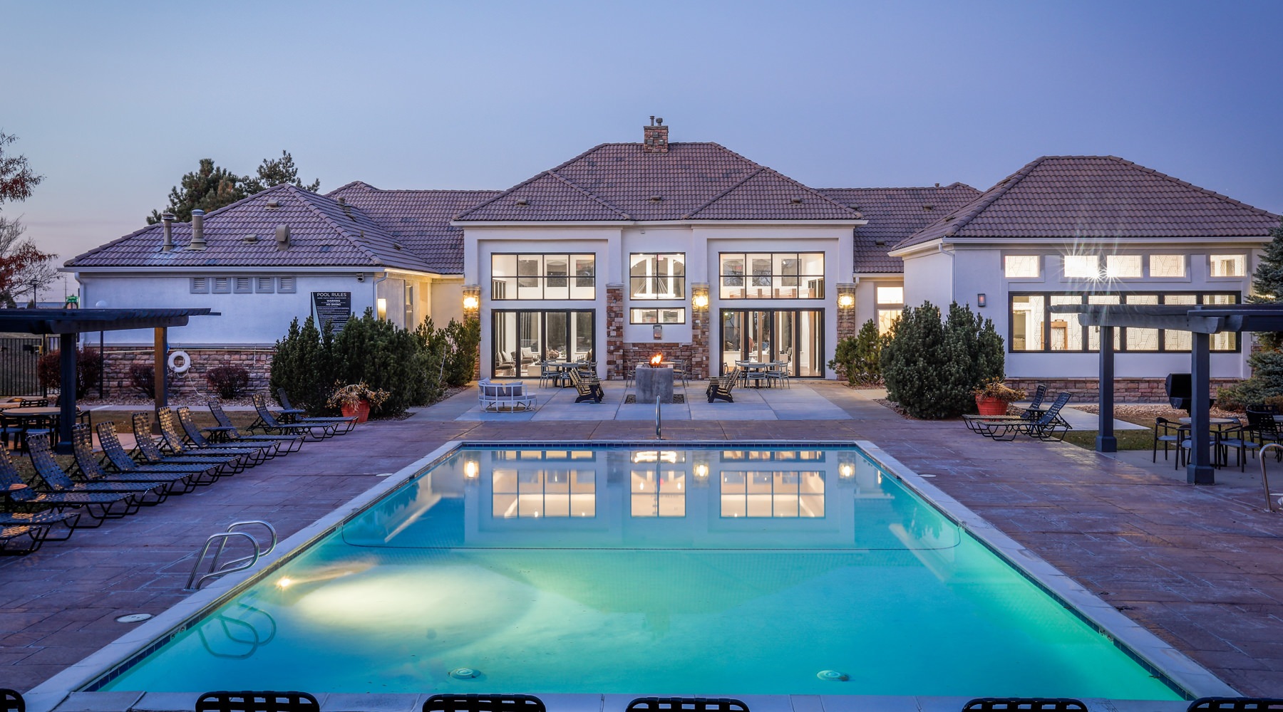 The clubhouse at Legacy at Highlands Ranch Apartments is illuminated at dusk, with a swimming pool in the foreground. The clubhouse at Legacy at Highlands Ranch Apartments is illuminated at dusk, with a swimming pool in the foreground.
